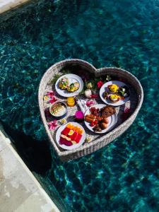 un vassoio di cibo a forma di cuore in piscina di La Roja Bungalows a Nusa Penida