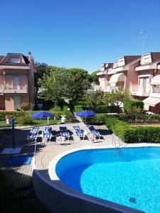 a swimming pool with chairs and umbrellas next to a building at B&C Apartments in Lido di Jesolo