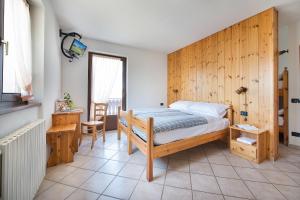 een slaapkamer met een bed en een houten muur bij Hotel Gallo Cedrone in Valdisotto