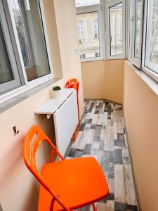 een oranje stoel in een kleine kamer met ramen bij Euro Apartment in Boekarest