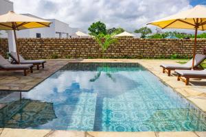 uma piscina com duas cadeiras e um guarda-sol em 4 U Luxury Bungalows Diani em Praia de Diani