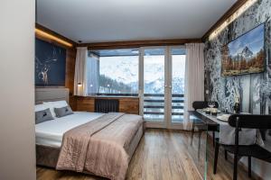 a bedroom with a bed and a desk and a window at DEER LODGE in Breuil-Cervinia