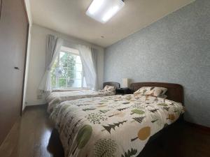 Biei Snow House - Vacation STAY 14827 في بيي: غرفة نوم مع سرير مع لحاف و نافذة