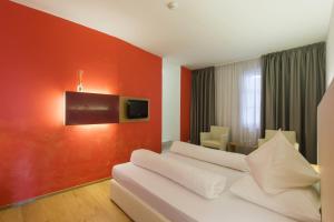 a hotel room with a white couch and a red wall at Hotel Goldener Stern in Caldaro