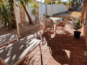 a patio with a table and chairs and an umbrella at BEACH 400m, Big Yard, Playroom, Perfect for Families, Couples, Digital Nomads in Mandurah