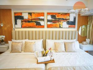 a bedroom with a large bed with two paintings on the wall at Casa Arabella - Wind Residences Tower 5 2018 in Tagaytay