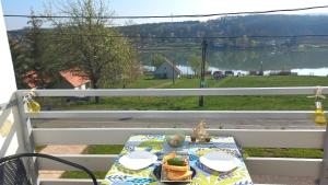 a table on a porch with a view of a lake at Onix-Vital Apartman Orfű in Orfű