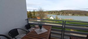 a balcony with a table and chairs and a view of the water at Onix-Vital Apartman Orfű in Orfű