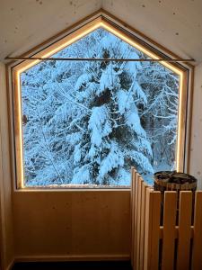 una ventana en una habitación con un árbol cubierto de nieve en Salzbergalm, en Berchtesgaden