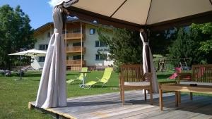 una terrazza in legno con ombrellone, sedie e parco giochi di B&B Hotel Heidi a Dobbiaco