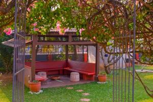 - un banc rouge dans un kiosque dans un jardin dans l'établissement Skylark Resort, à Colva