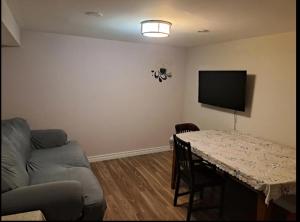 uma sala de estar com uma mesa e um sofá em Cozy room at walkout basement em Pickering