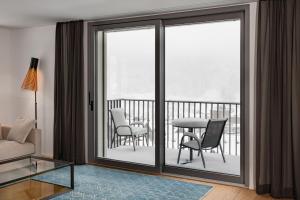 sala de estar con puertas correderas de cristal con mesa y sillas en Swiss Hotel Apartments - Engelberg, en Engelberg