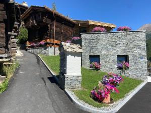 ein Steingebäude mit Blumen davor in der Unterkunft Chalet Coral und Zermatter Stadel mit Sauna in Zermatt