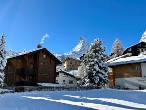 ein schneebedecktes Dorf mit einem Berg im Hintergrund in der Unterkunft Chalet Coral und Zermatter Stadel mit Sauna in Zermatt