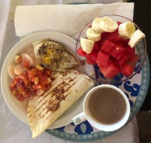 un plato de comida con un tazón de fruta y una taza de café en Refugio Cariguana, en El Valle de Antón