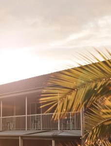 a building with a balcony and a palm tree at Holiday Lodge Motor Inn in Narooma