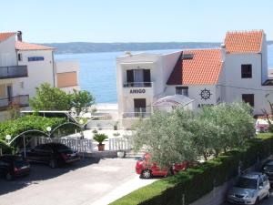 un edificio con auto parcheggiate di fronte all'acqua di Villa Amigo a Podstrana