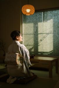 une femme regarde par une fenêtre dans l'établissement 大吉屋日赤館貸切一軒家旅館新築名古屋駅圏内, à Nagoya