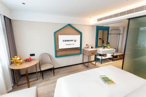 広州市にあるGuangzhou Yilin Hotelの鏡、テーブル、洗面台が備わる客室です。