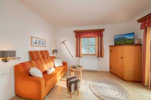 uma sala de estar com um sofá laranja e uma janela em Molteraugut em Mühlbach am Hochkönig