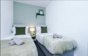 twee bedden in een kamer met groen en wit bij St Helens - Cosy 1 Bed in Saint Helens