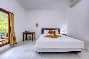 um quarto com uma cama branca e uma janela em Ari La Casa em Nusa Penida