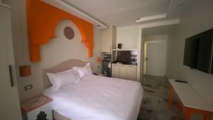 a bedroom with a white bed and an orange wall at Amman Trail Hotel & Studios in Amman