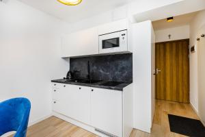 a kitchen with white cabinets and a microwave at Grapa Ski - apartament Białka Tatrzańska in Białka Tatrzanska