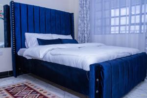 uma cama grande com uma cabeceira azul num quarto em Tiny Haven executive one bedroom with Private Balcony em Nanyuki