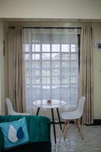 uma sala de estar com um sofá, uma mesa e uma janela em Tiny Haven executive one bedroom with Private Balcony em Nanyuki