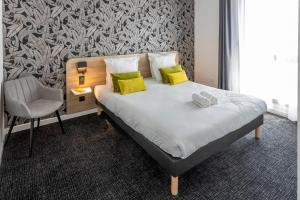 a bedroom with a bed with yellow pillows and a chair at Nemea Appart Hotel Nice Arenas Aéroport in Nice