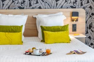 a tray of food on a bed with yellow pillows at Nemea Appart Hotel Nice Arenas Aéroport in Nice