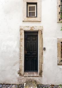 una porta nera sul lato di un edificio bianco di Casa Aurora - bairro típico a minutos do Terreiro a Lisbona