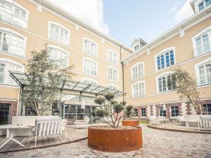 um grande edifício com mesas e bancos num pátio em Mercure Troyes Centre em Troyes