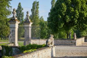 pies siedzący na płocie przed bramą w obiekcie Chateau d'Audrieu w mieście Audrieu