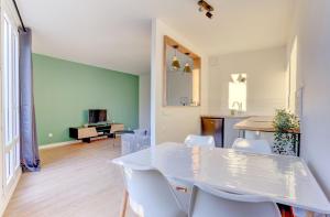 a white dining room with a white table and chairs at Le Petit Nid - Apt Lumineux en Hypercentre in Montigny-le-Bretonneux