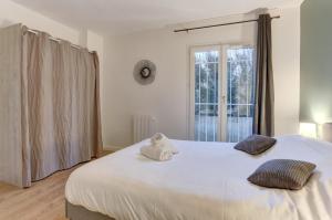 a bedroom with a large white bed with a teddy bear on it at Le Petit Nid - Apt Lumineux en Hypercentre in Montigny-le-Bretonneux