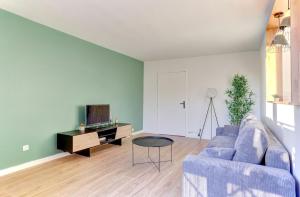 a living room with a blue couch and a tv at Le Petit Nid - Apt Lumineux en Hypercentre in Montigny-le-Bretonneux