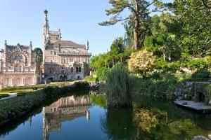 a building and a river in front of a building at Palace Hotel do Bussaco in Luso