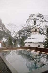 - une vue sur une église avec une montagne enneigée dans l'établissement Hotel Fiescherblick, à Grindelwald