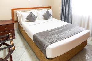 - un lit avec des draps et des oreillers blancs dans l'établissement Emboita Hotel Limited, à Nakuru