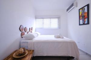 - une chambre blanche avec un lit et une fenêtre dans l'établissement Heritage Residences Santo Domingo, à Saint-Domingue