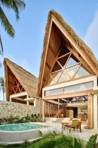 een huis met een rieten dak en een zwembad bij Tias Villas in Kuta Lombok