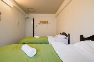 3 camas en una habitación con verde y blanco en Fukuoka Share Hotel, en Fukuoka