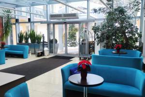 a lobby with blue chairs and tables and windows at Hotel *** NAT Kołobrzeg in Kołobrzeg