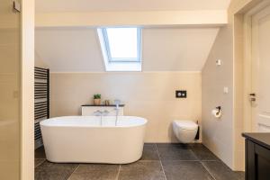 a bathroom with a white tub and a toilet at Villa Zuiderduin in Zoutelande