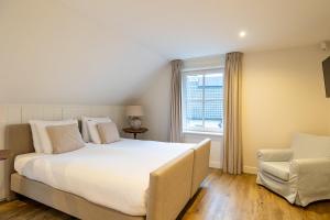 a bedroom with a large white bed and a chair at Villa Zuiderduin in Zoutelande