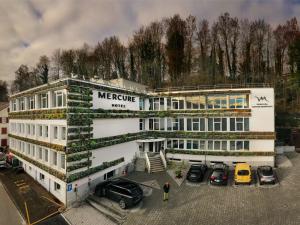 um grande edifício branco com carros estacionados num parque de estacionamento em Mercure Fribourg Centre Remparts em Fribourg