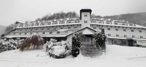 ein großes Gebäude mit einem Auto im Schnee in der Unterkunft Apartman Nina, Kopaonik, Brzeće, Kod Gondole in Brzeće